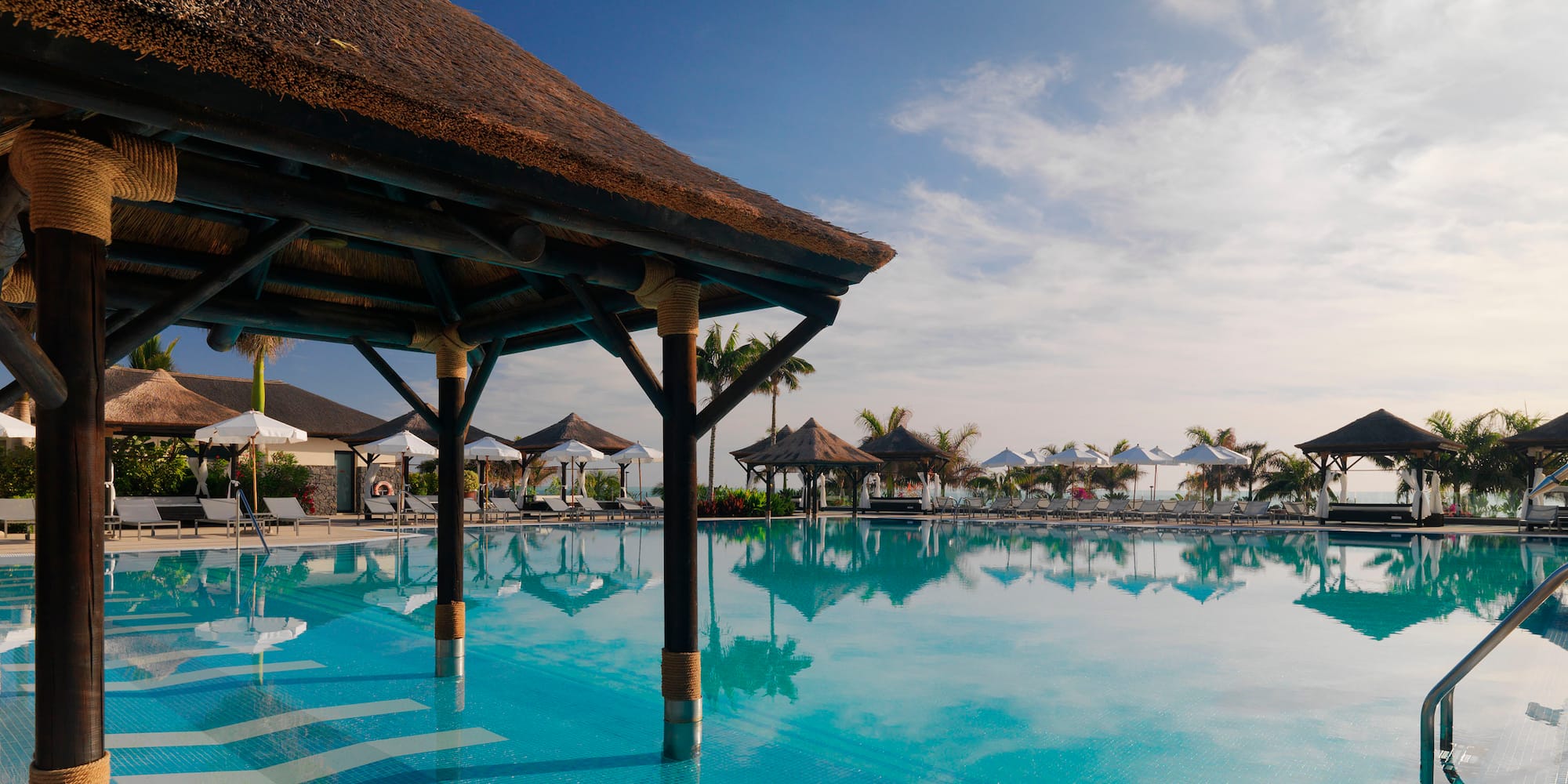 a pool with umbrellas and a thatched roof