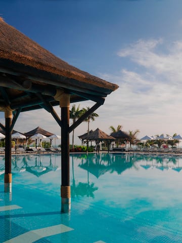 a pool with umbrellas and a thatched roof