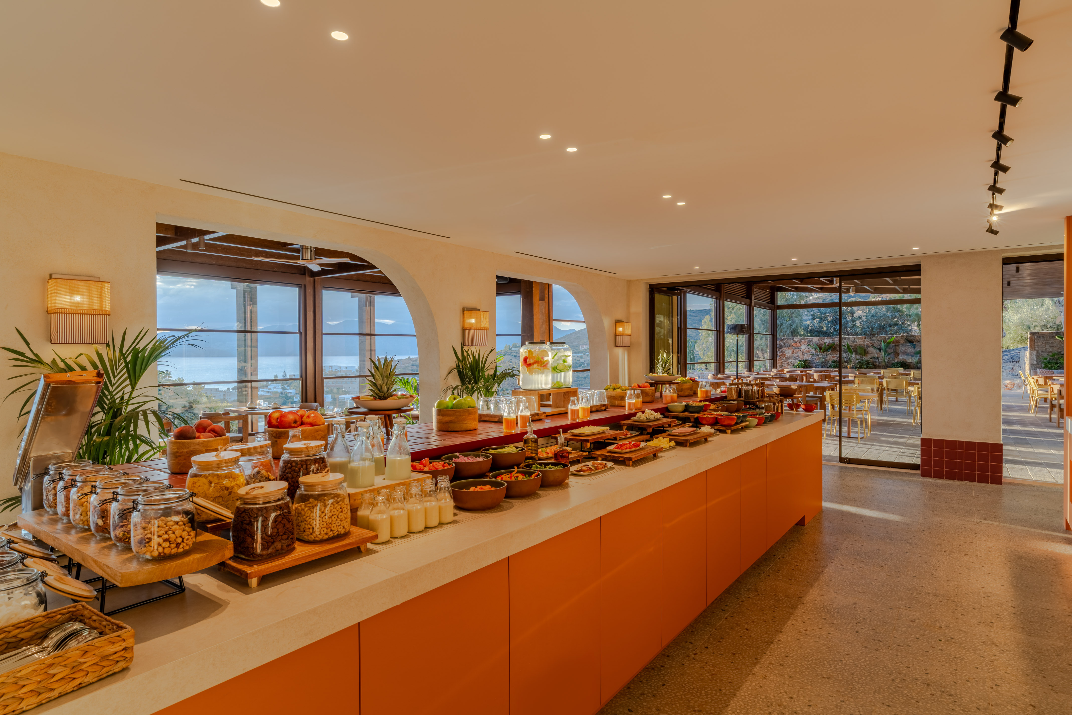 Spacious hotel breakfast buffet with fresh food, cereals, fruits, and ocean view.
