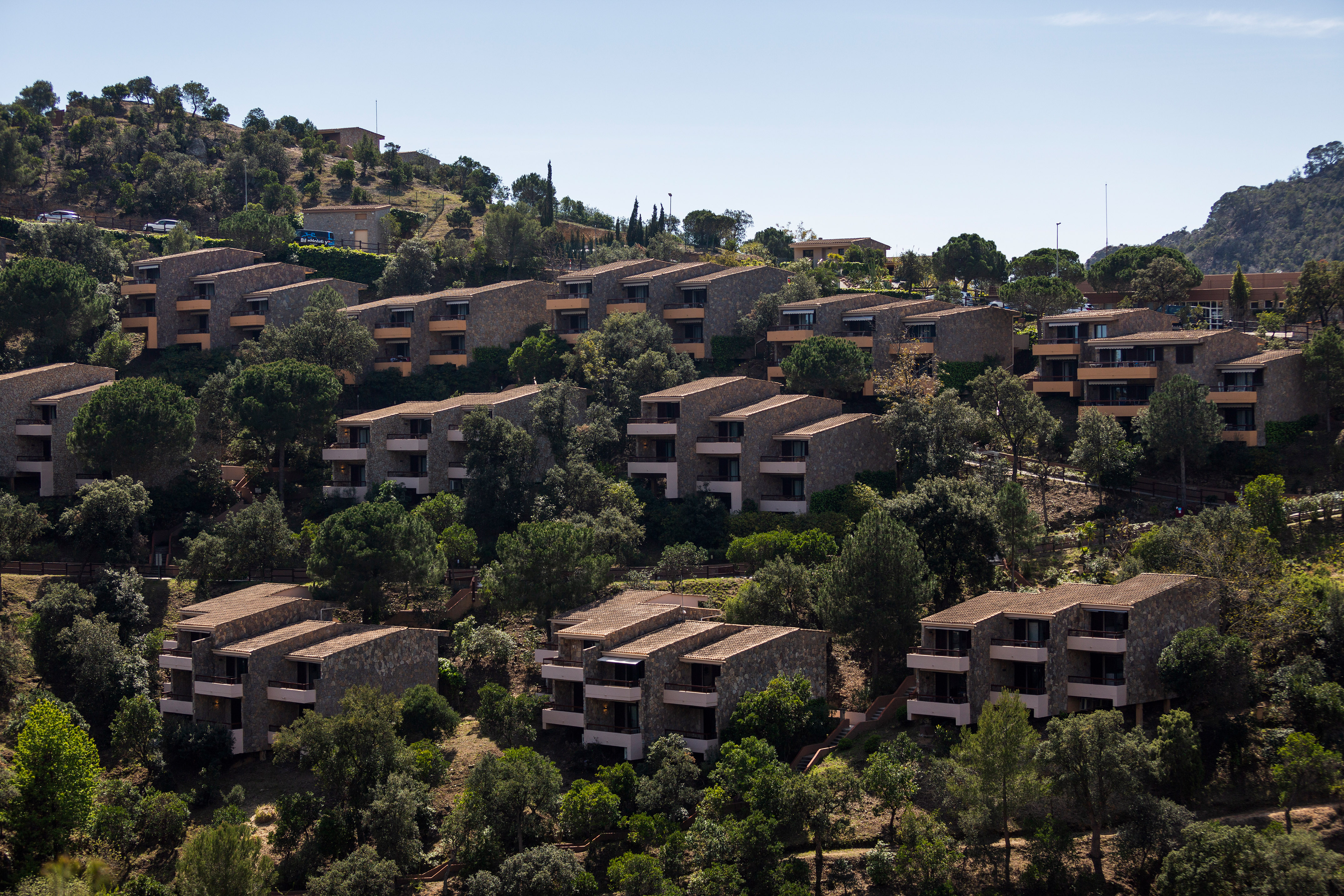 Terraced stone resort buildings with balconies on a green hillside.