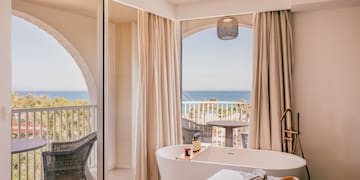 a room with a bathtub and a window with a view of the ocean