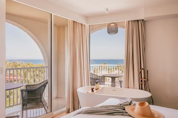 a room with a bathtub and a window with a view of the ocean