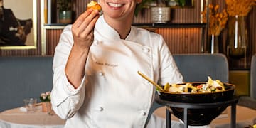 a woman in a chef's uniform holding food