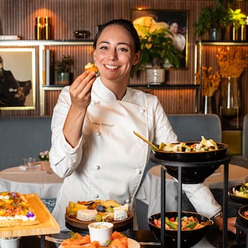 a woman in a chef's uniform holding food