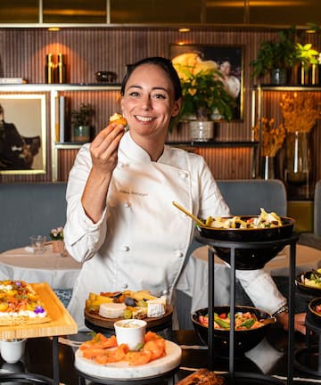 a woman in a chef's uniform holding food