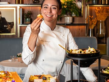 a woman in a chef's uniform holding food