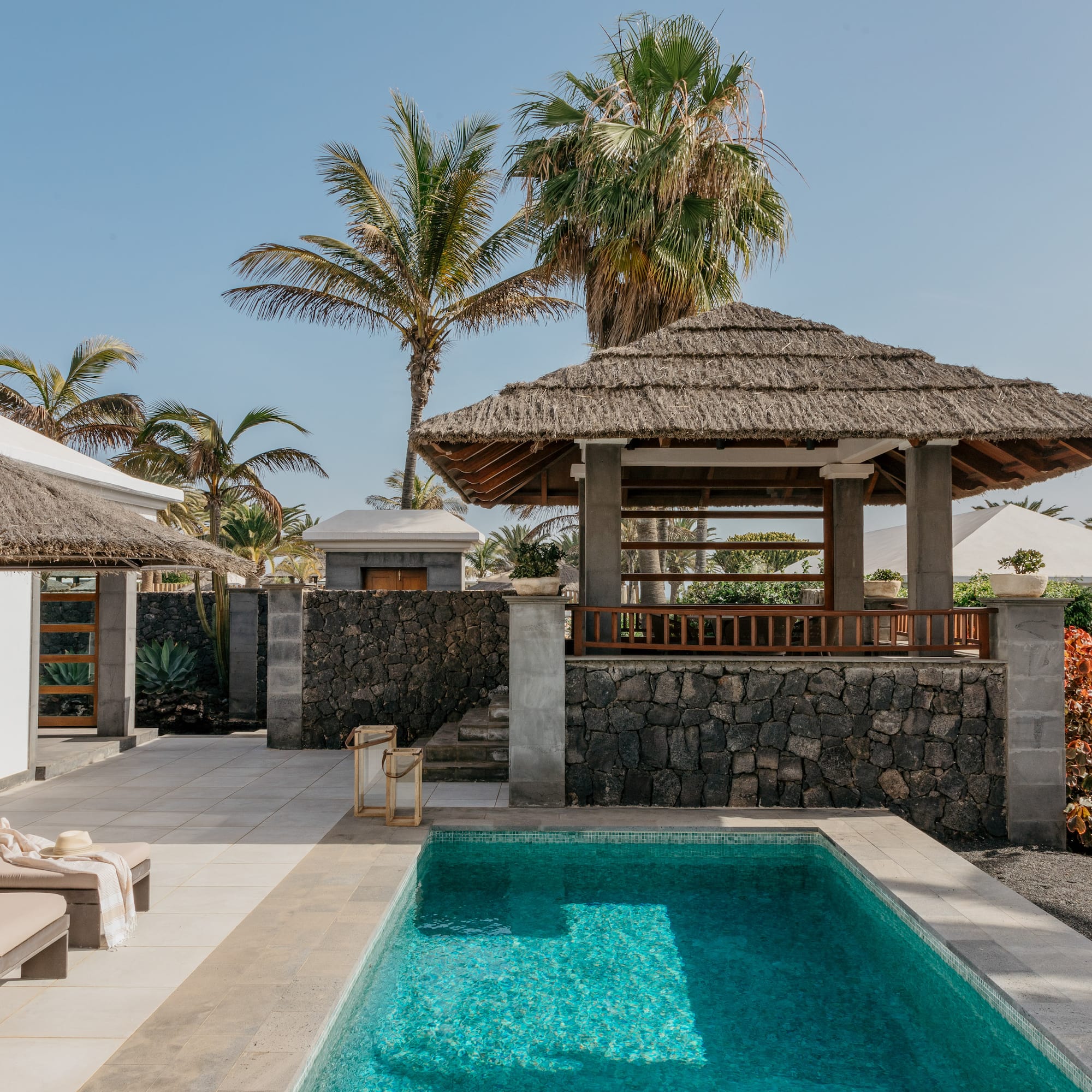a pool with a gazebo and palm trees