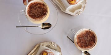 a hand holding a cup of coffee and pastries