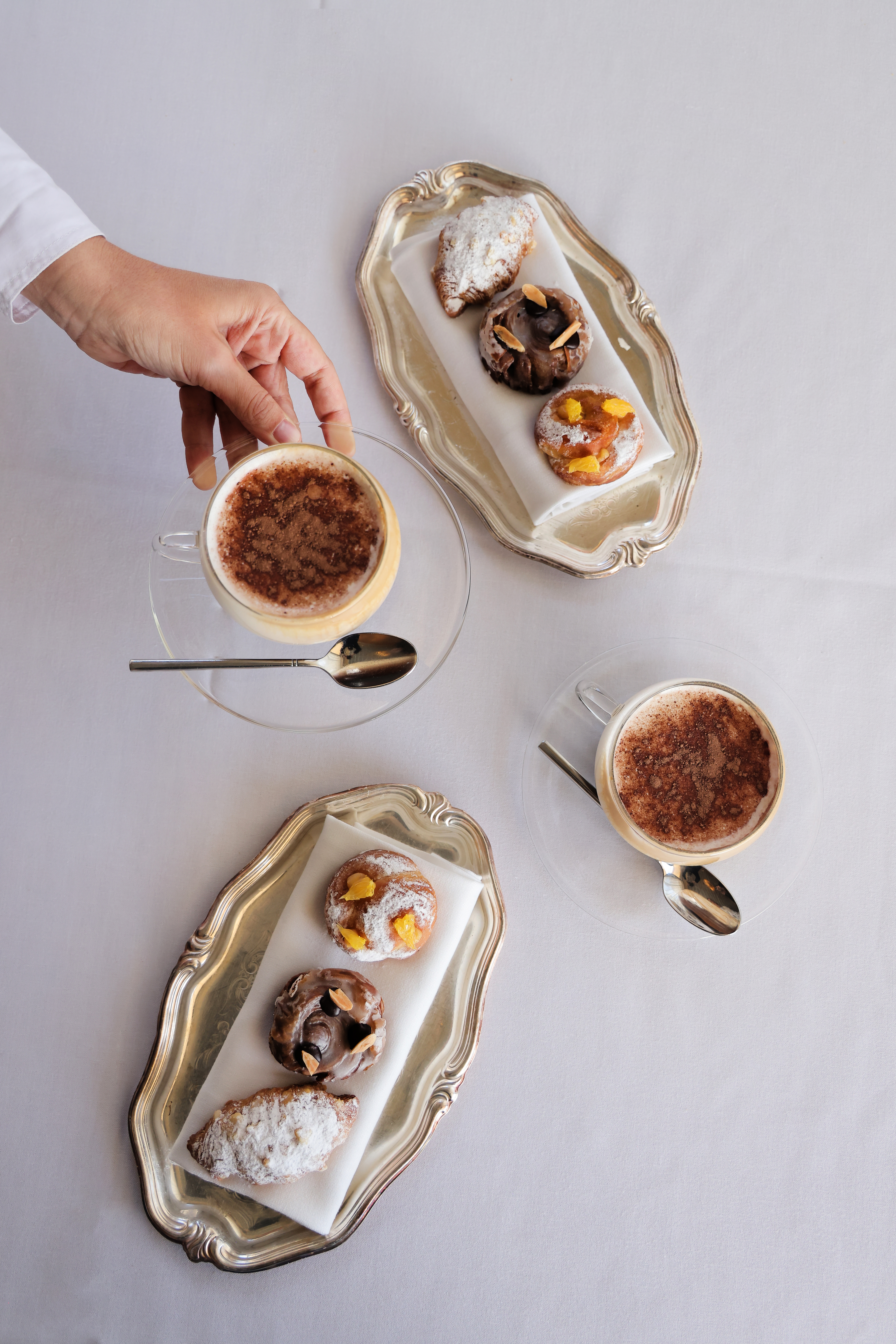 a hand holding a cup of coffee and pastries