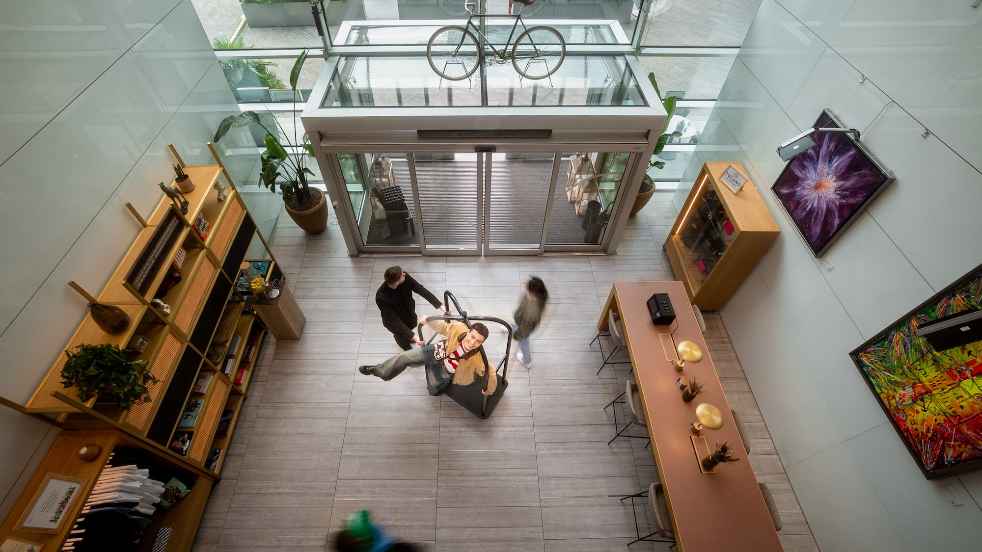 Man on suspended interactive display in a modern glass atrium with bicycle.