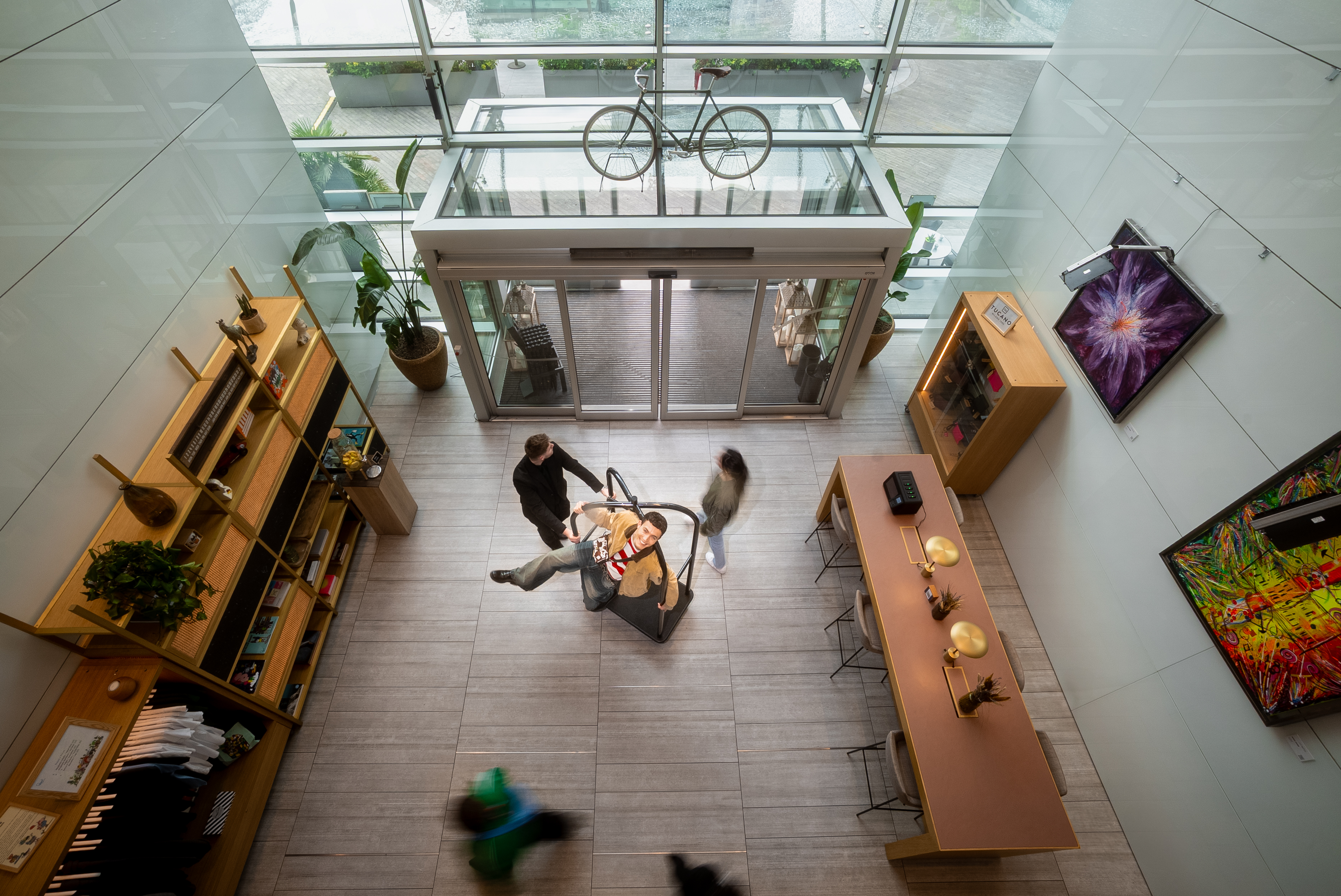 Man on suspended interactive display in a modern glass atrium with bicycle.