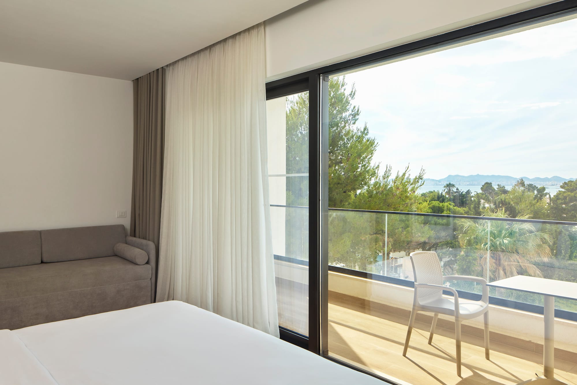 a room with a bed and a chair and a balcony