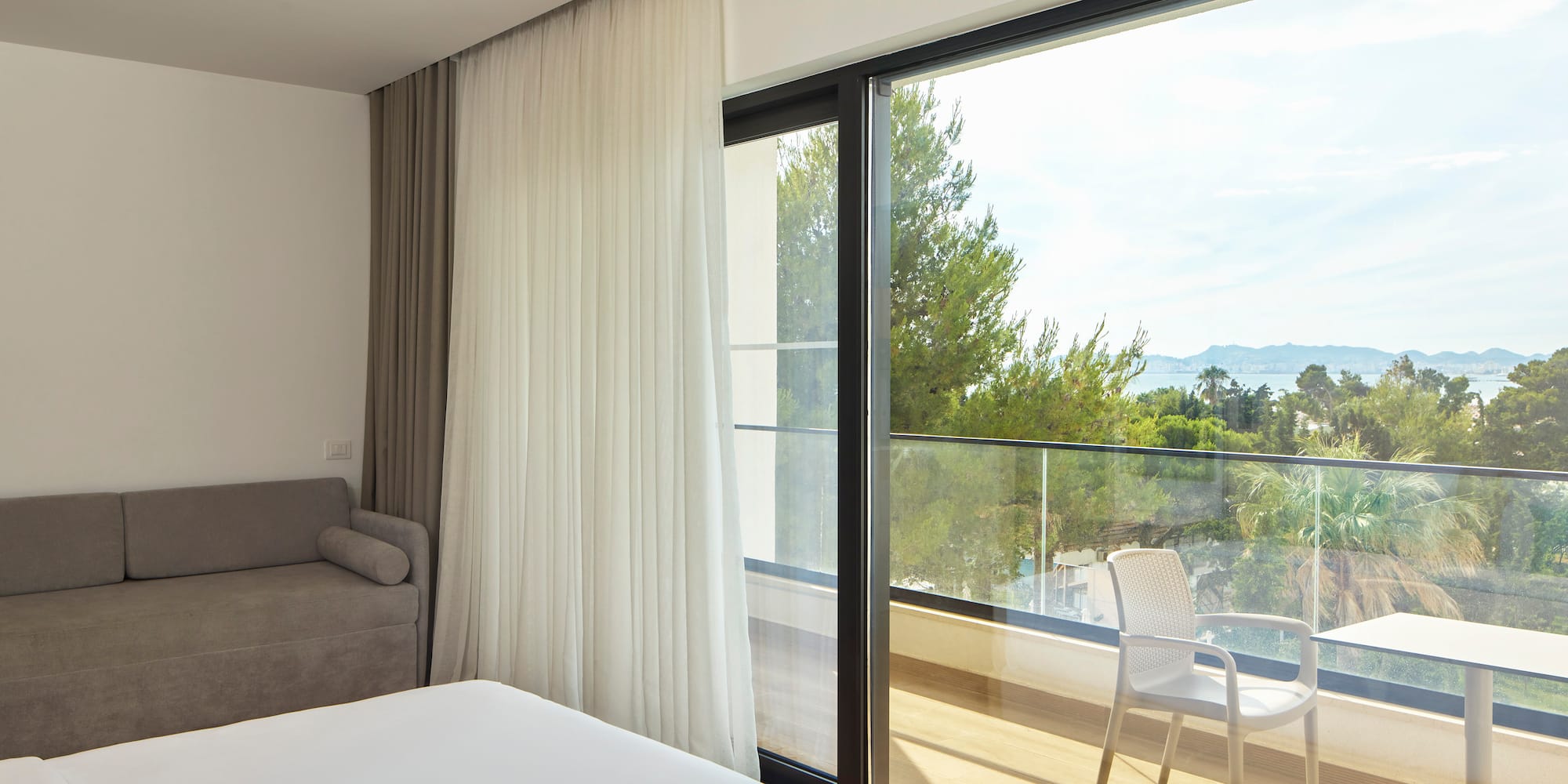 a room with a bed and a chair and a balcony