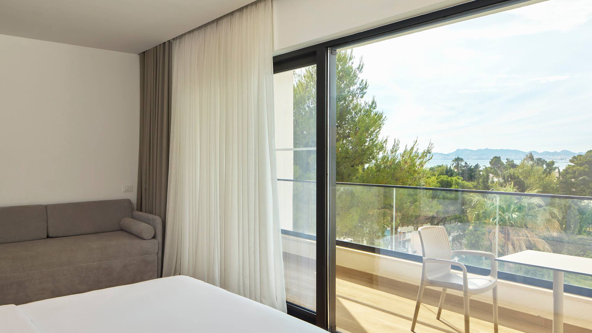 a room with a bed and a chair and a balcony