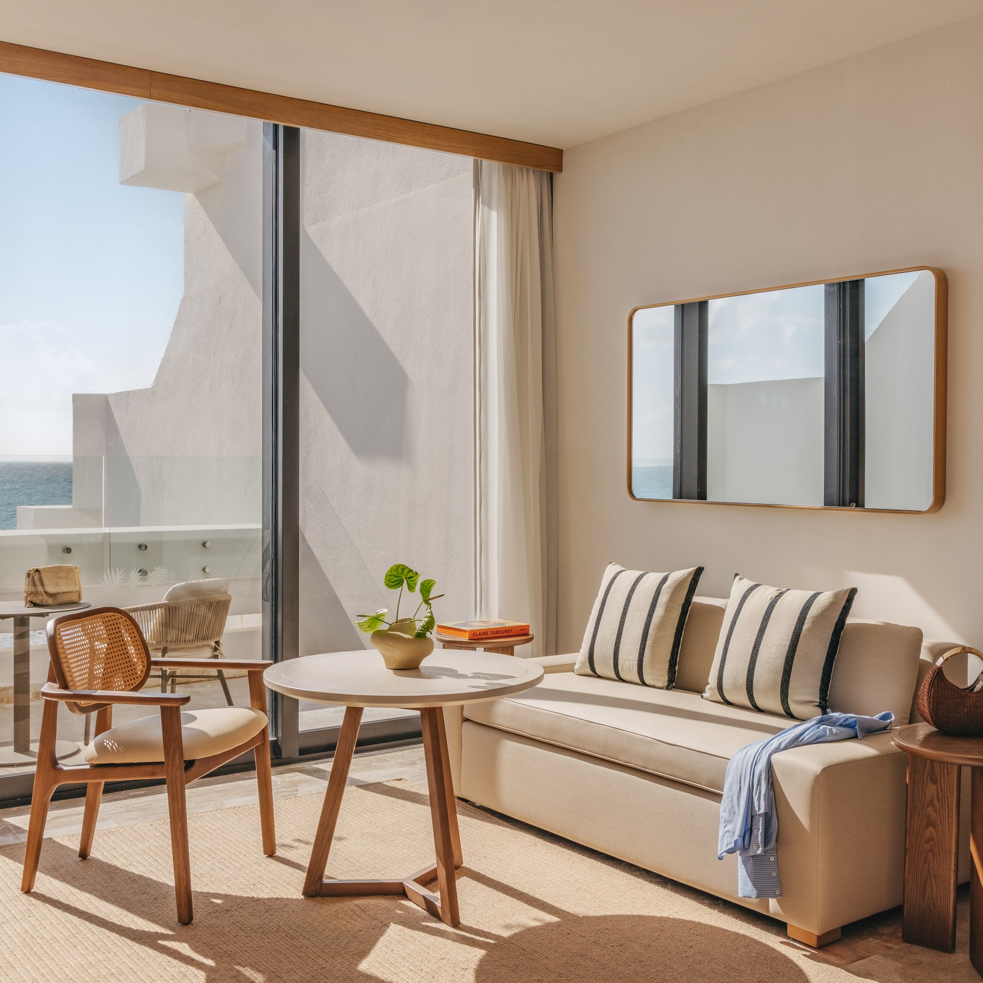 Modern oceanfront hotel room with balcony, sofa, coffee table, and sea view.