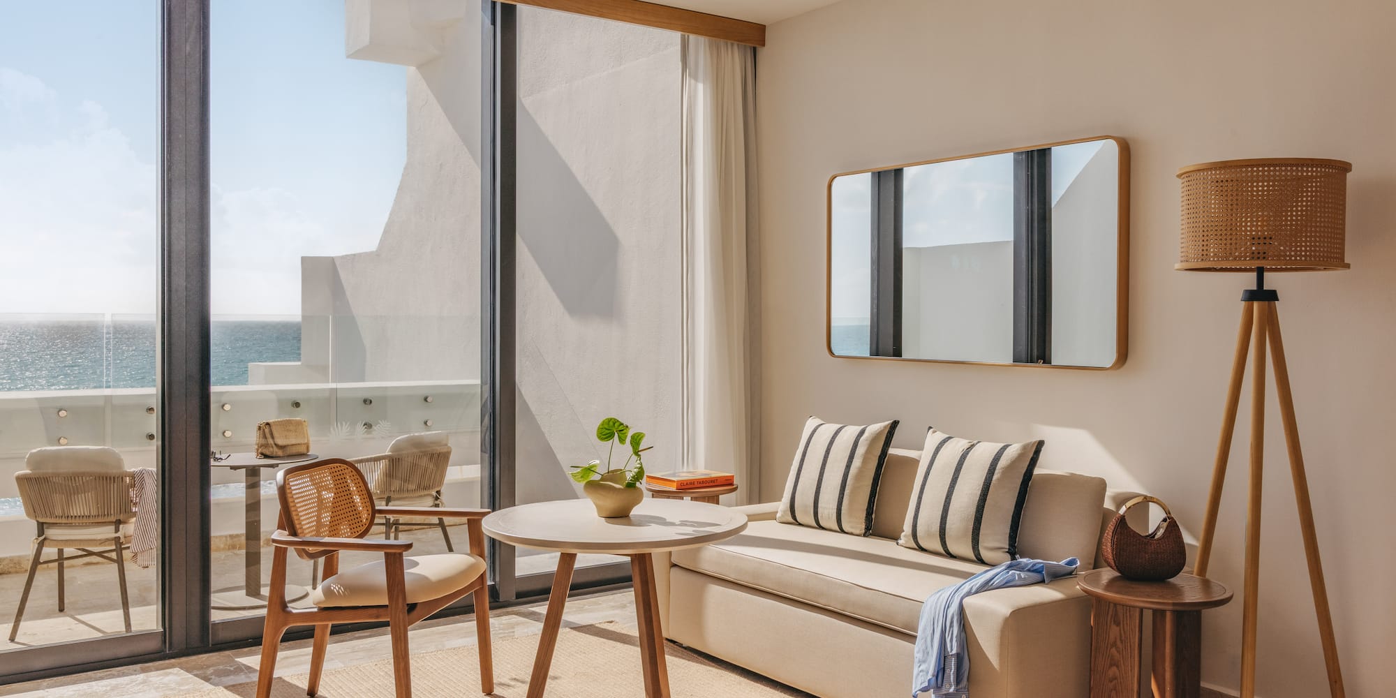 Modern oceanfront hotel room with balcony, sofa, coffee table, and sea view.