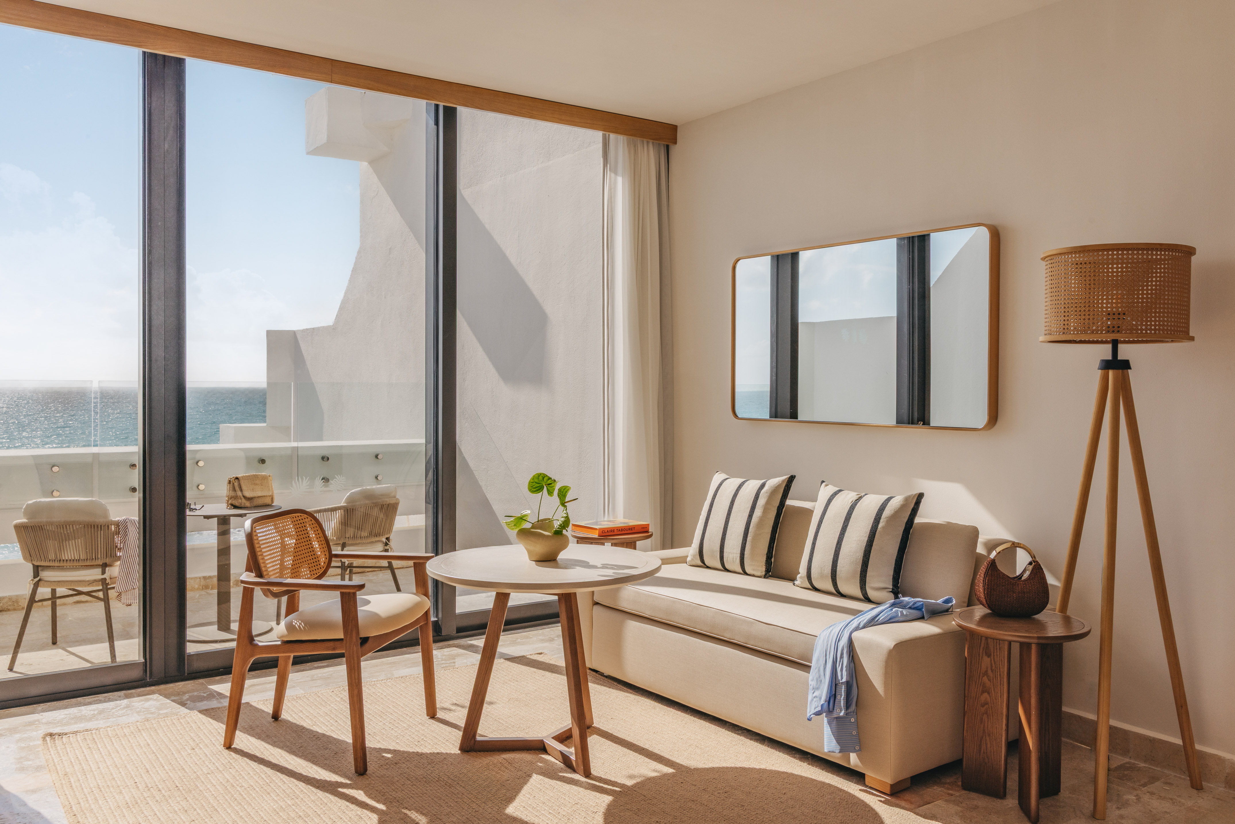Modern oceanfront hotel room with balcony, sofa, coffee table, and sea view.