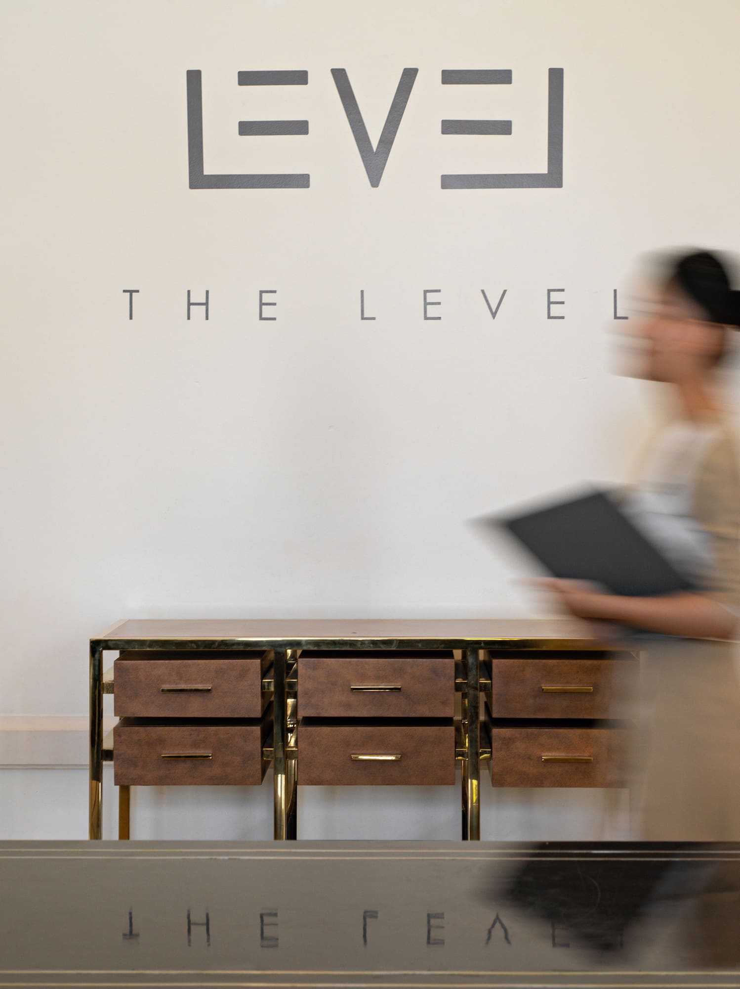 Elegant The Level reception with blurred staff, modern wood and gold cabinet.