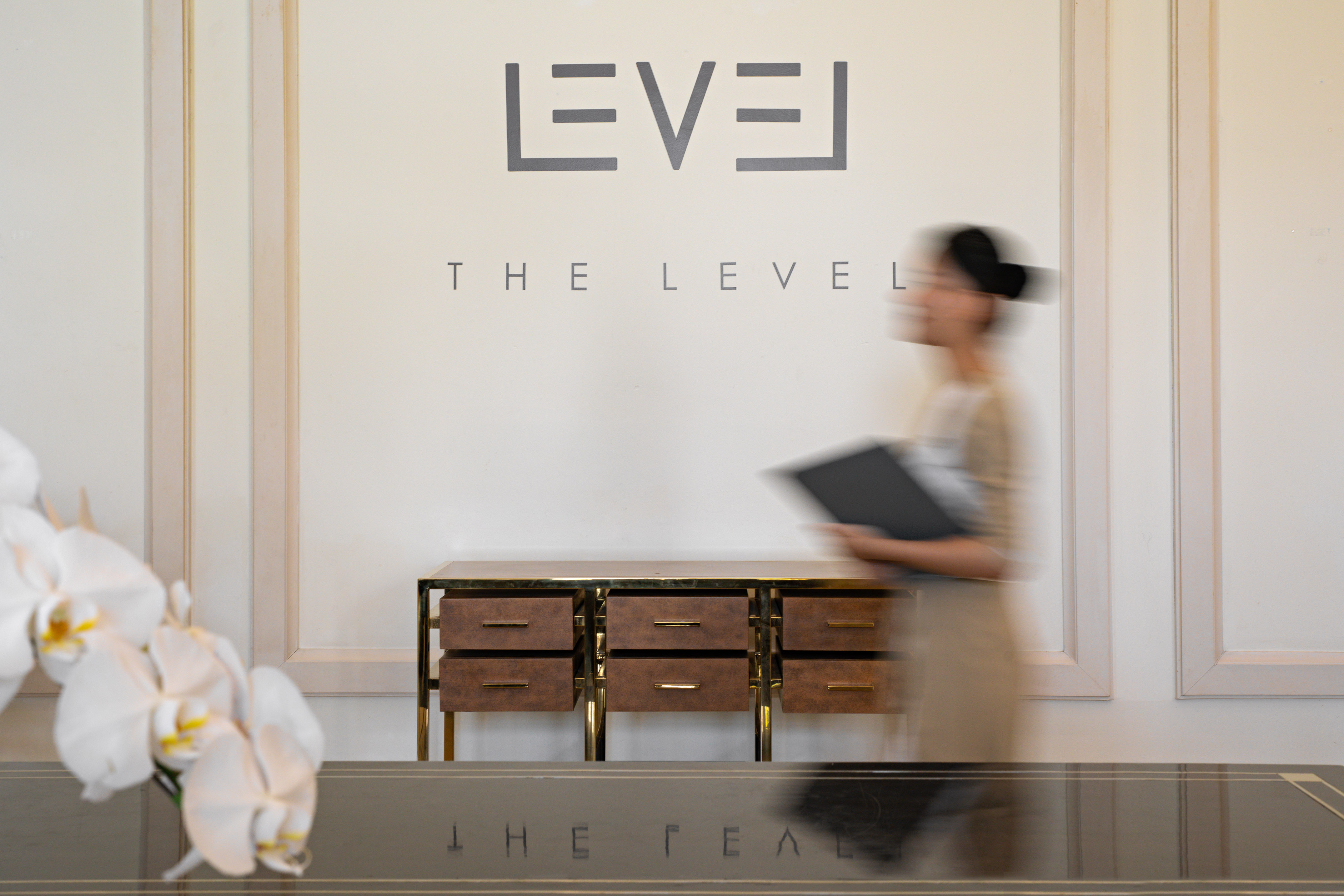 Elegant The Level reception with blurred staff, modern wood and gold cabinet.