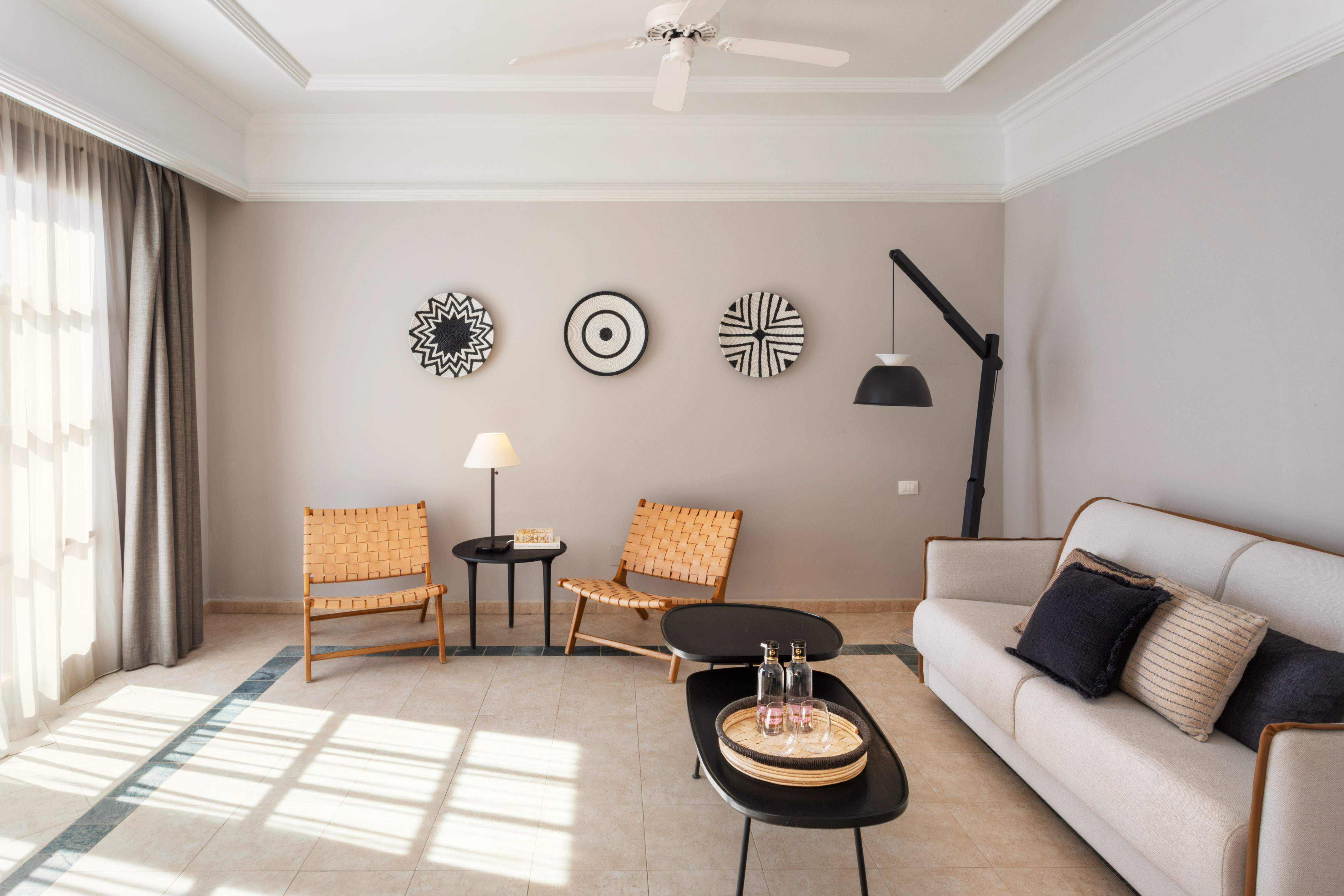 Modern living room with neutral sofa, woven chairs, and black-white wall art.