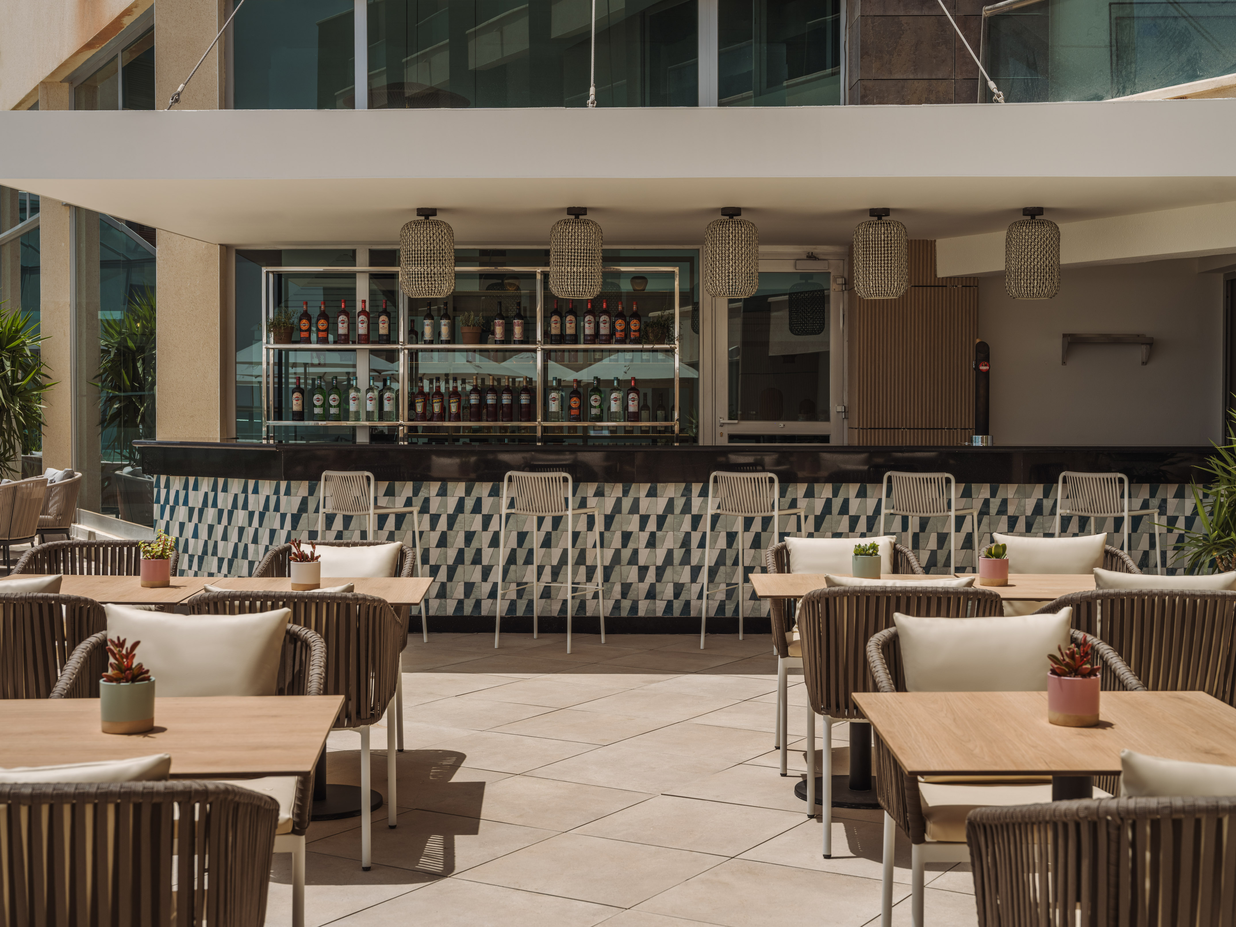 Outdoor bar patio, geometric tile counter, bottles, modern seating.