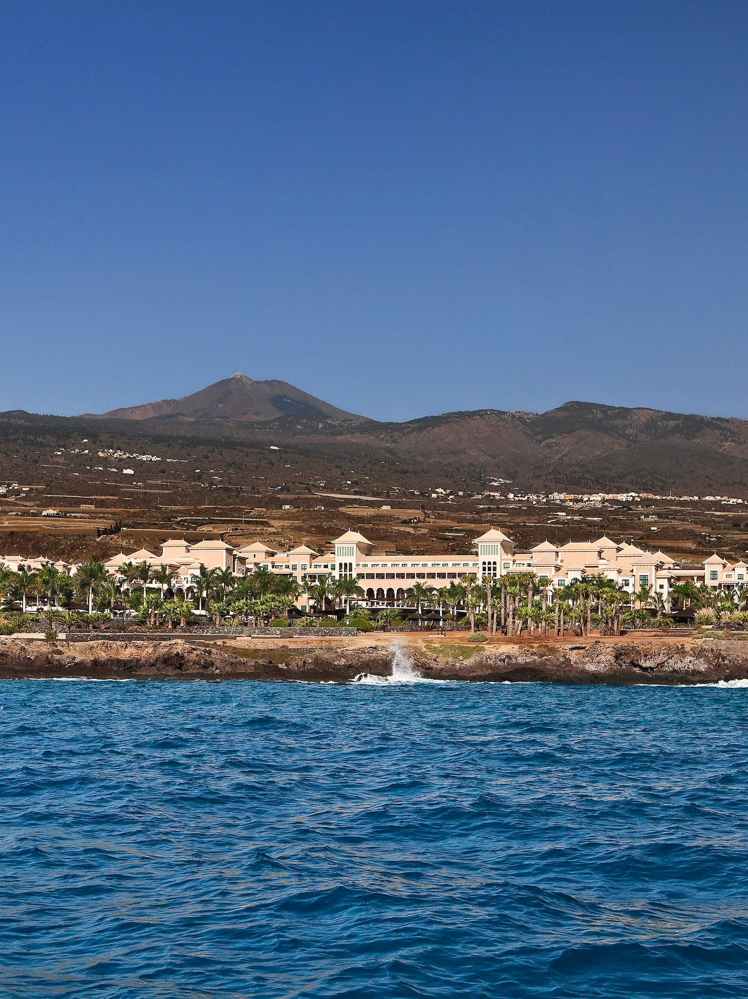 a body of water with buildings and mountains in the background