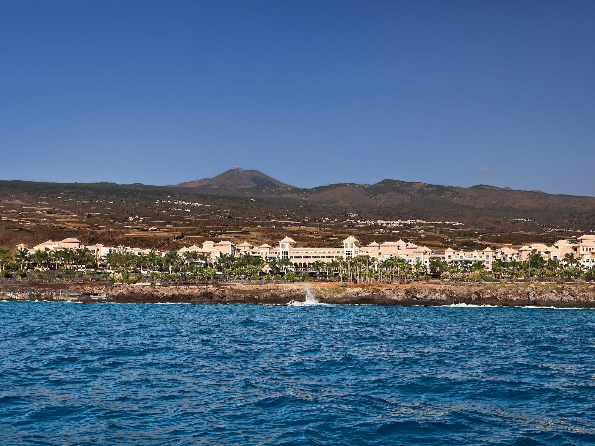 a body of water with buildings and mountains in the background