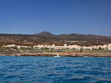 a body of water with buildings and mountains in the background