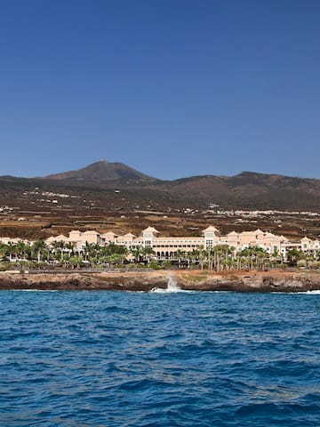 a body of water with buildings and mountains in the background