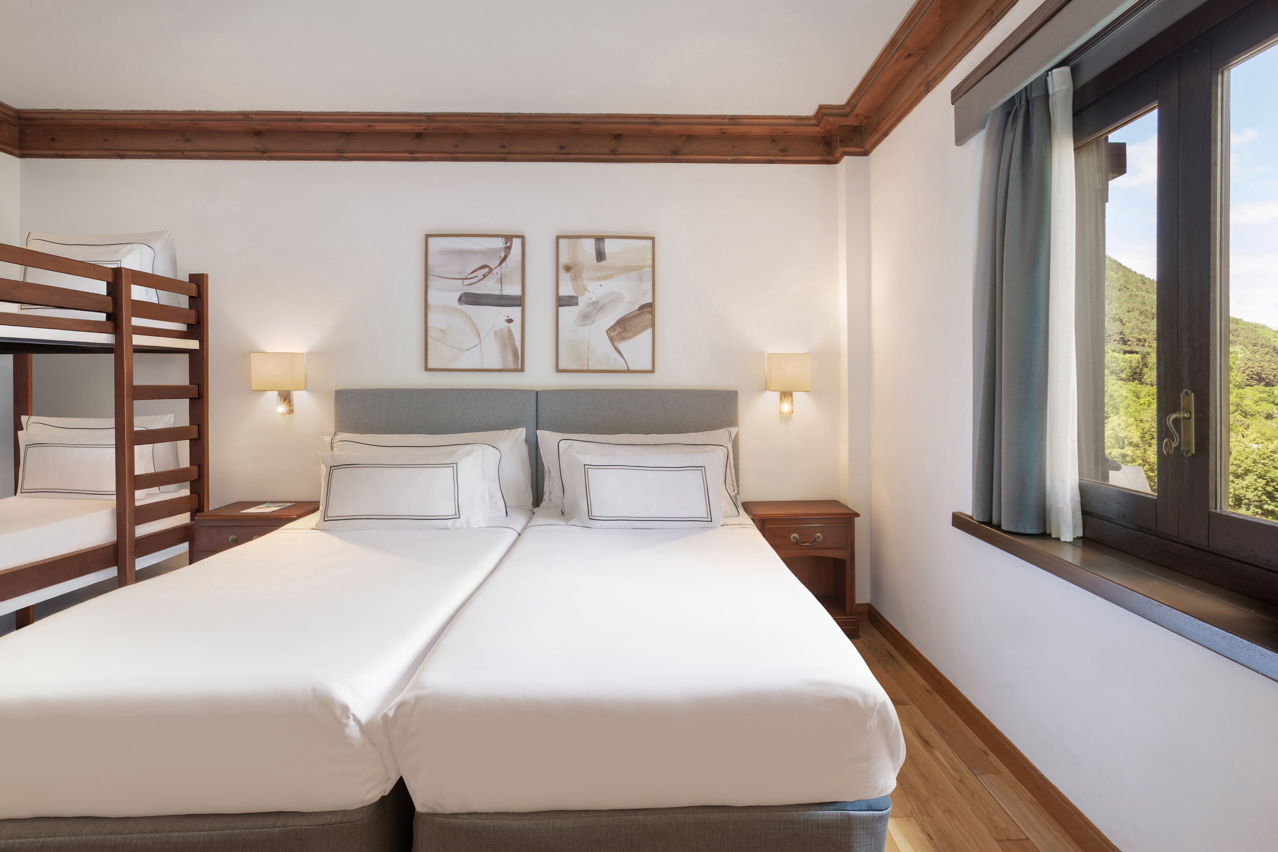 Hotel bedroom: twin beds, bunk bed, wood trim, mountain view.