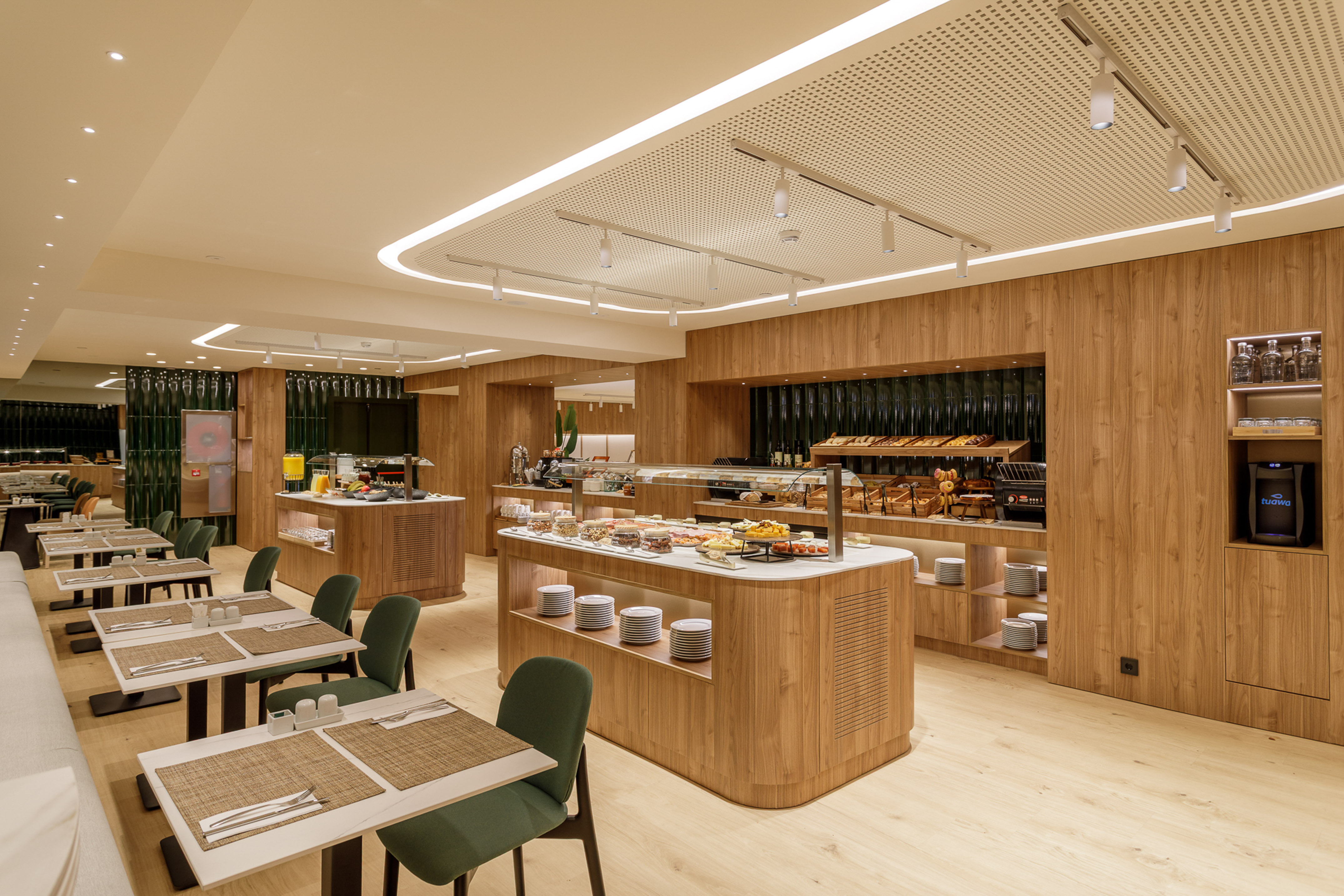 Hotel breakfast buffet with fresh food, modern wood decor, and dining tables.