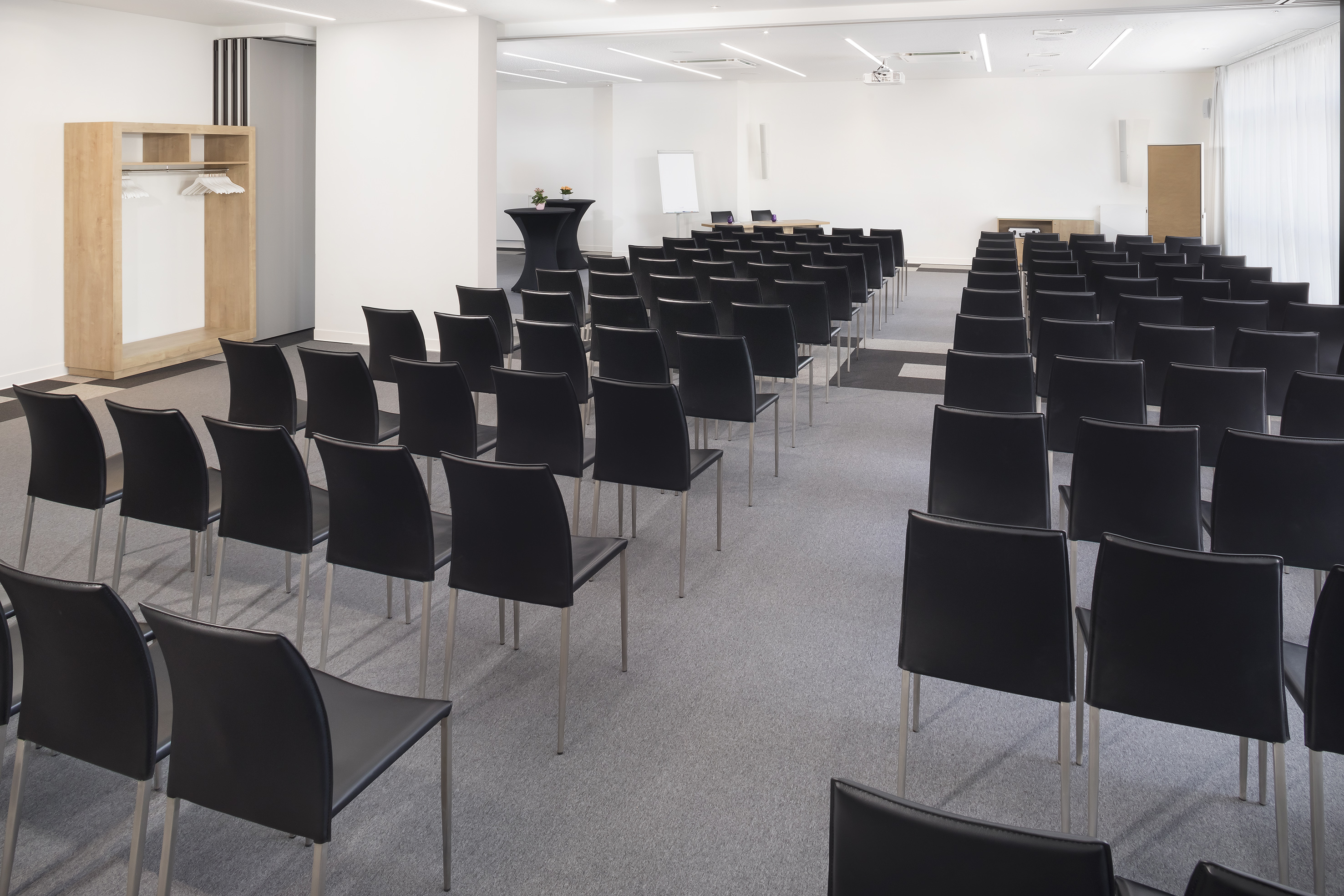 Modern conference room with black chairs, projector, and whiteboard.