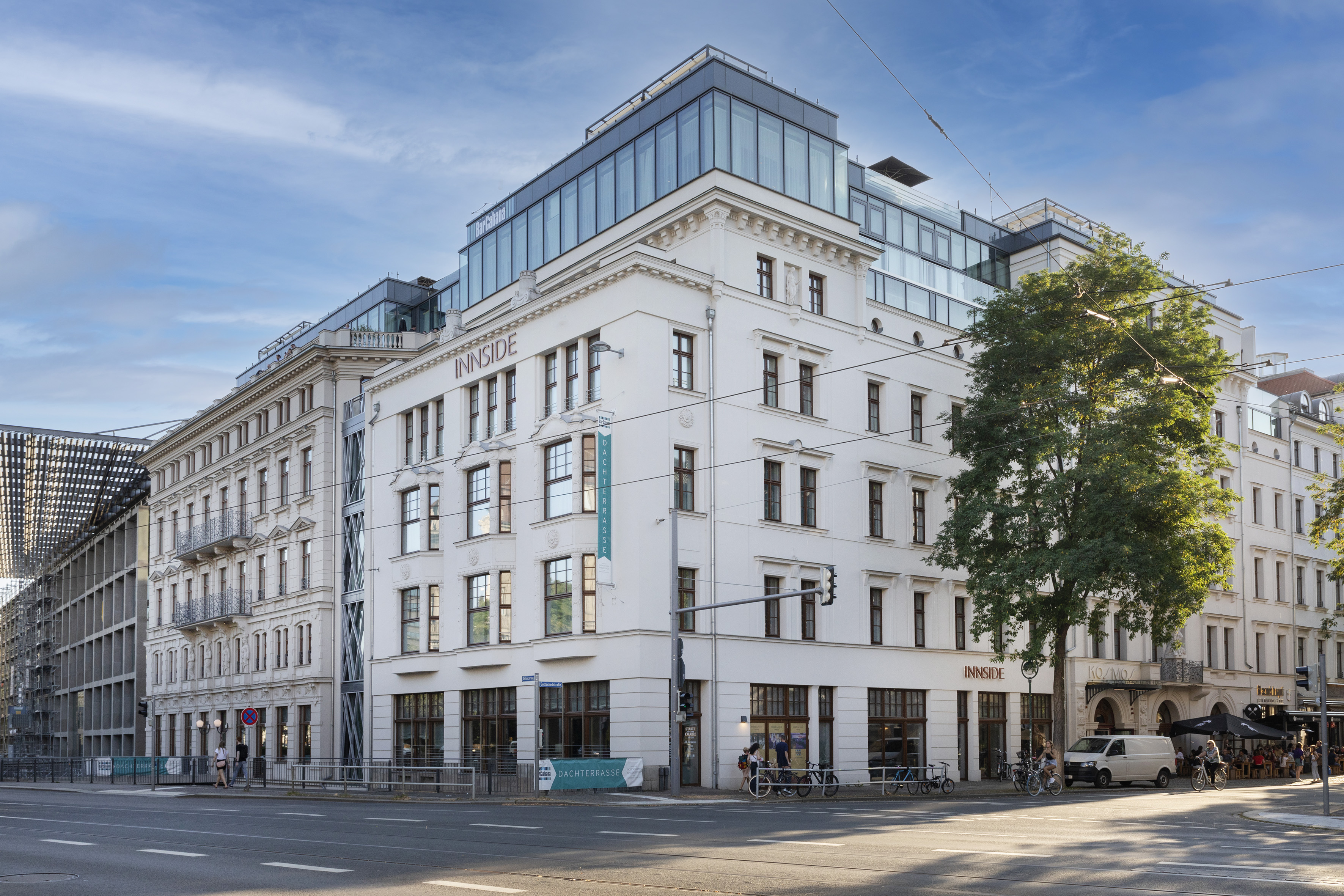 INNSIDE hotel building, white facade, modern glass rooftop, city street corner.