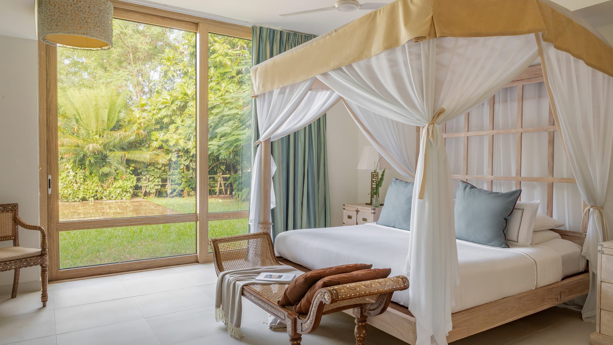 a bed with a canopy and a chair in a room with glass doors