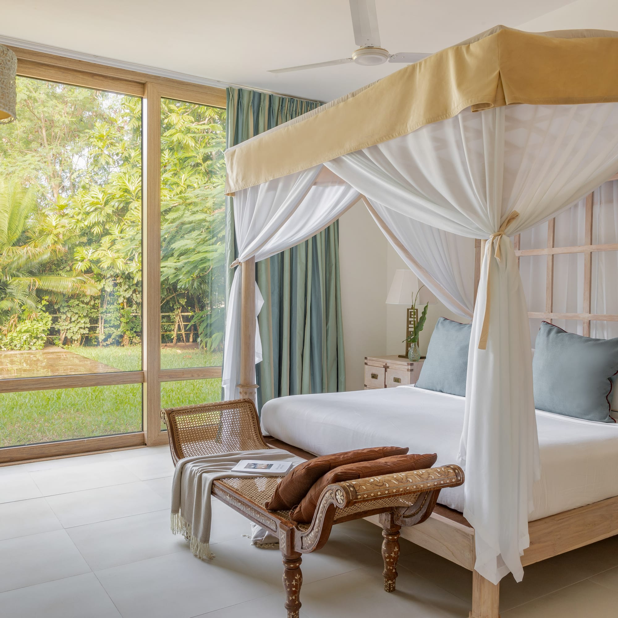 a bed with a canopy and a chair in a room with glass doors
