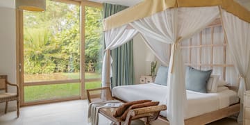 a bed with a canopy and a chair in a room with glass doors