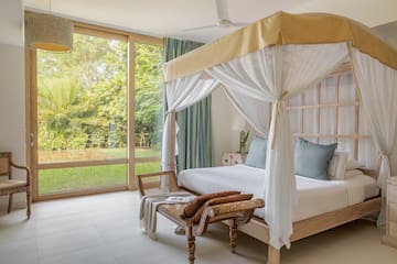 a bed with a canopy and a chair in a room with glass doors