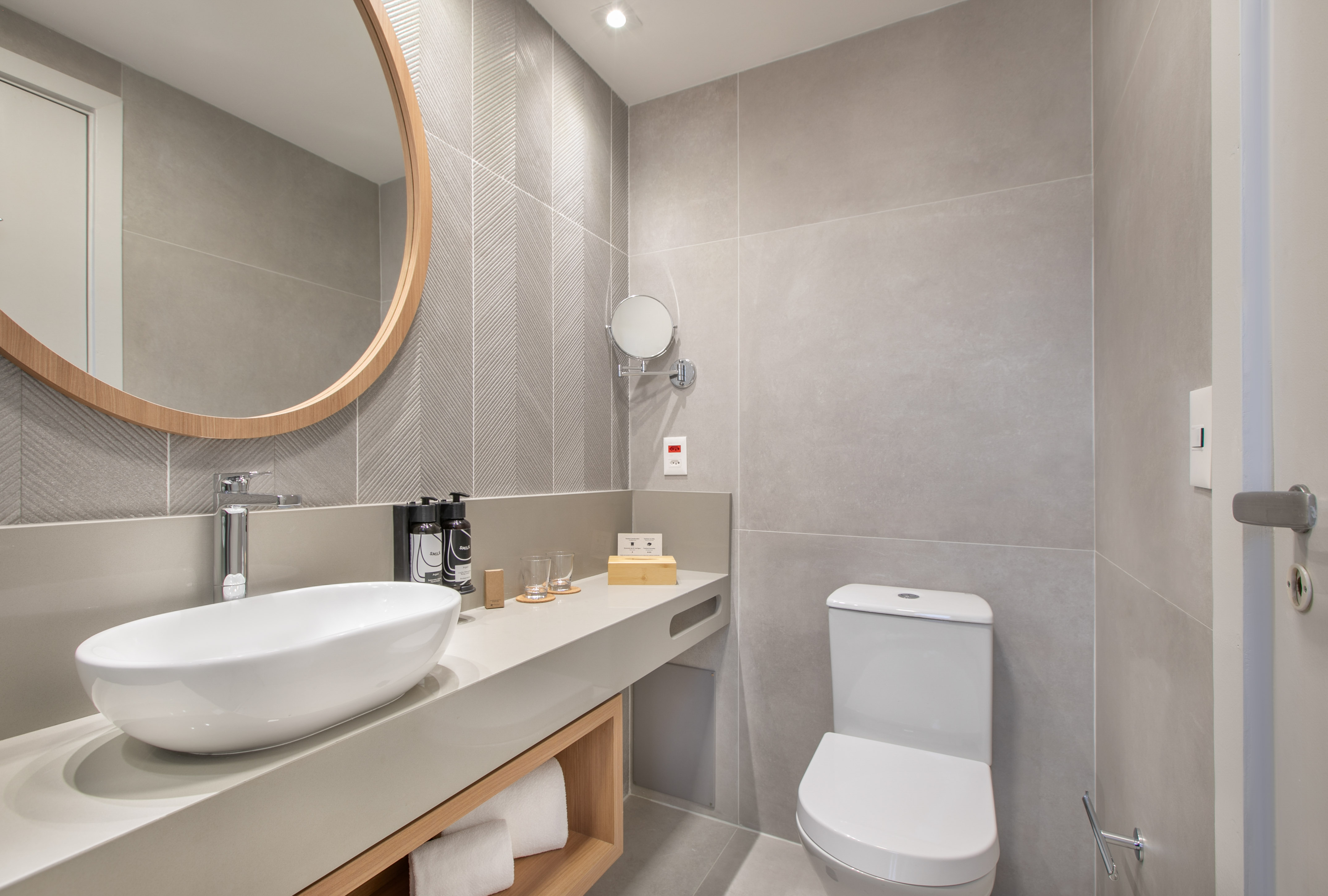a bathroom with a round mirror and sink