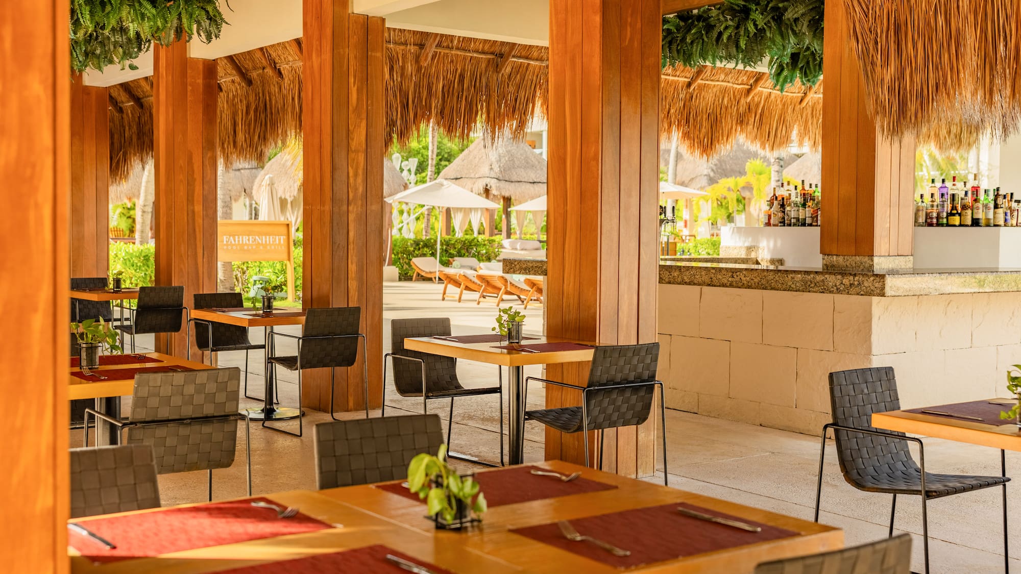 Outdoor resort dining with wooden tables, palapa roof, and full bar.
