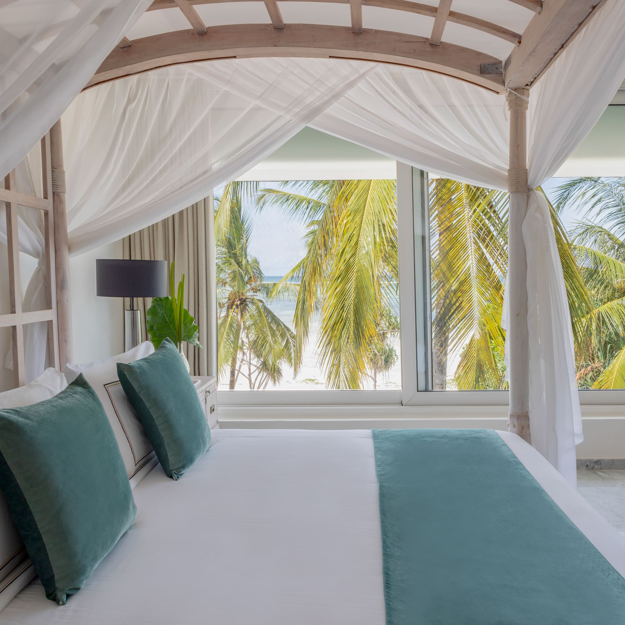 a bed with white sheets and green pillows