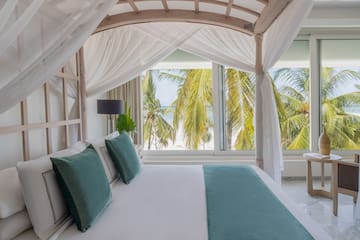 a bed with white sheets and green pillows
