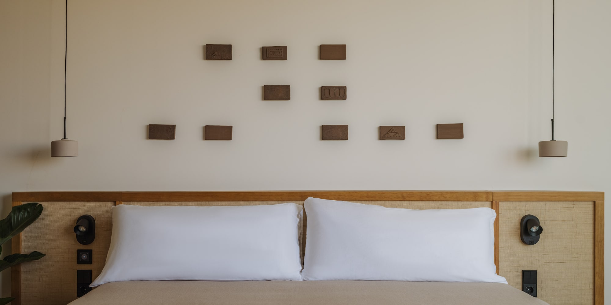 a bed with pillows and a lamp on the wall