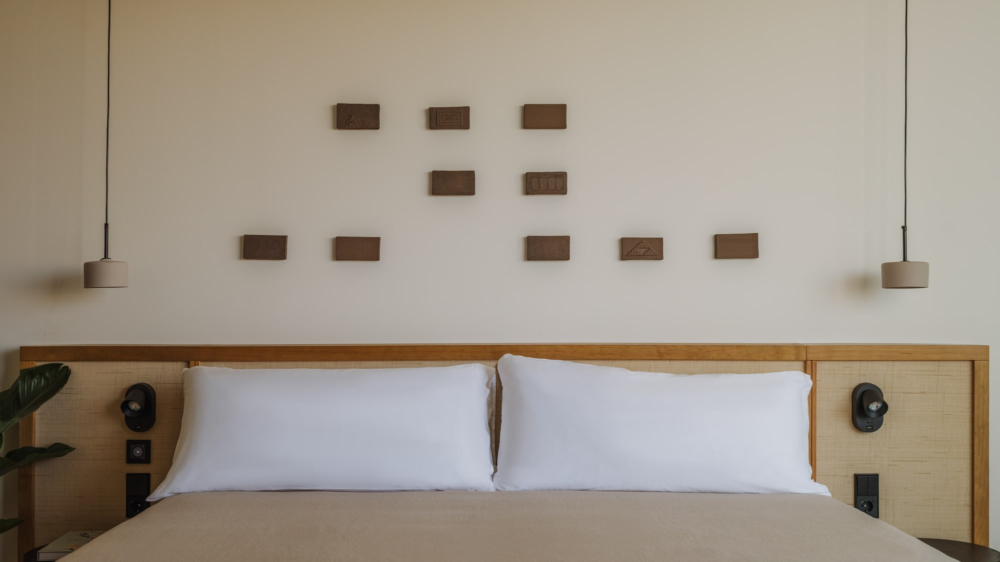 a bed with pillows and a lamp on the wall