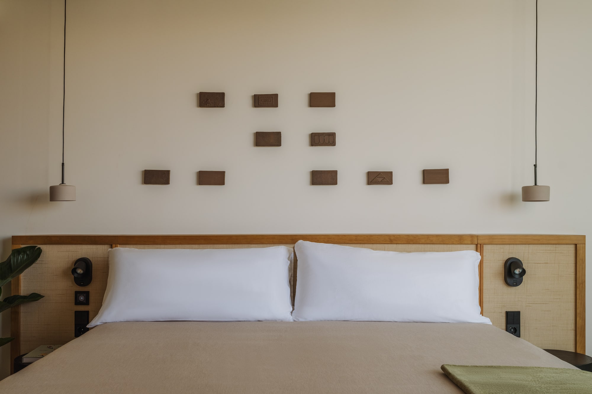 a bed with pillows and a lamp on the wall