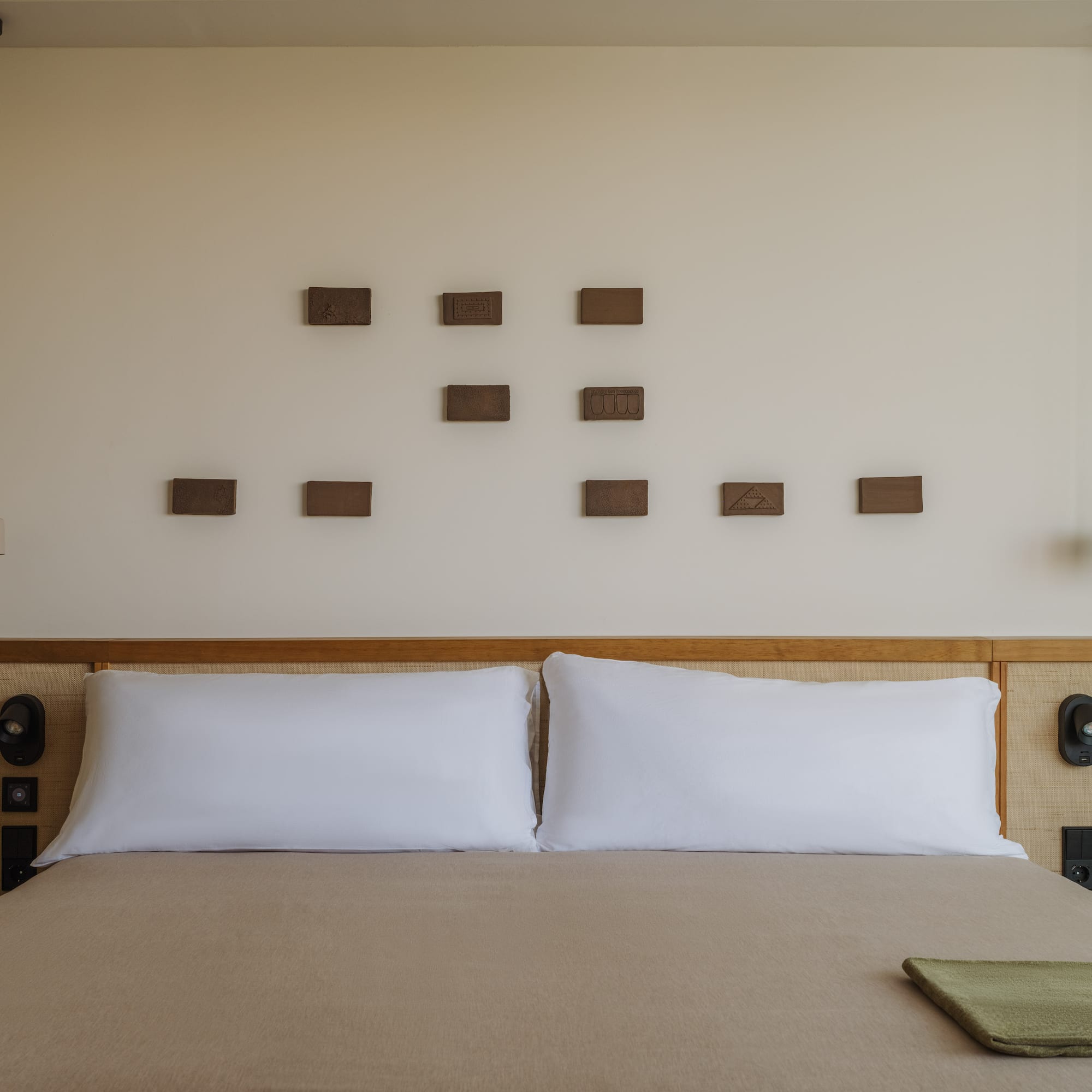 a bed with pillows and a lamp on the wall