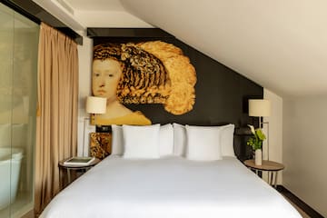 a bed with white sheets and a painting on the wall