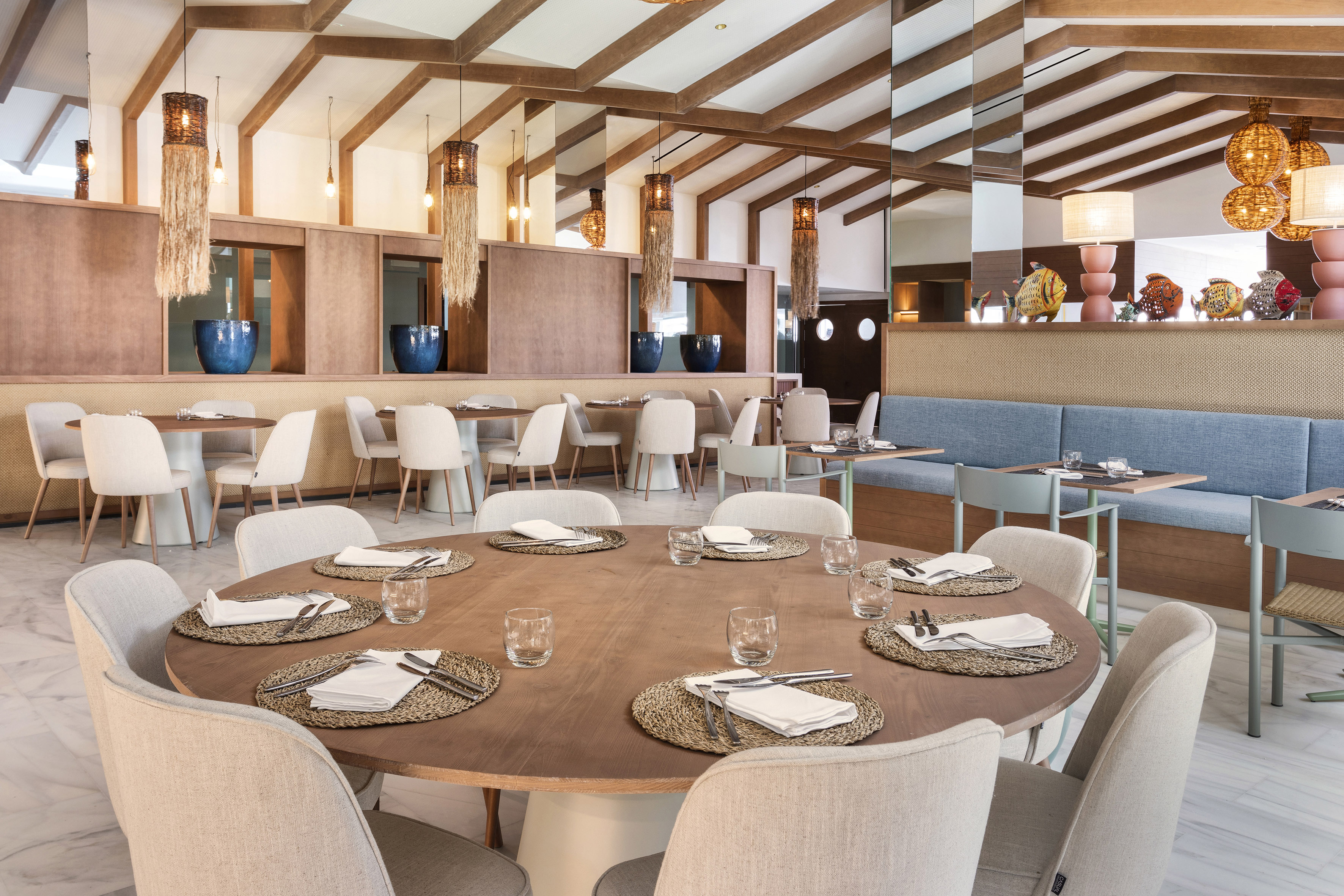 Modern restaurant with wooden tables, comfortable seating, and pendant lights.
