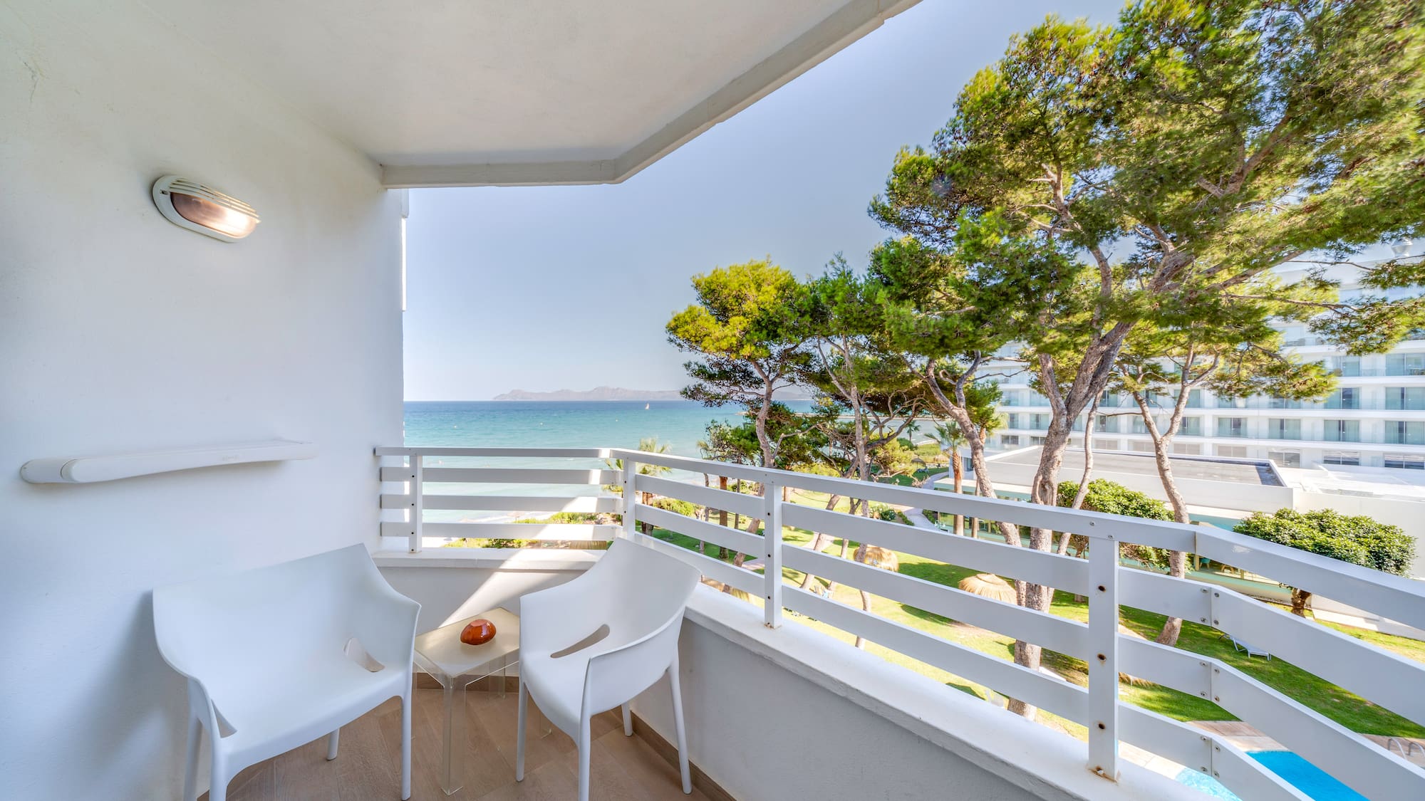 a white chairs on a balcony overlooking the ocean