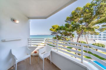 a white chairs on a balcony overlooking the ocean