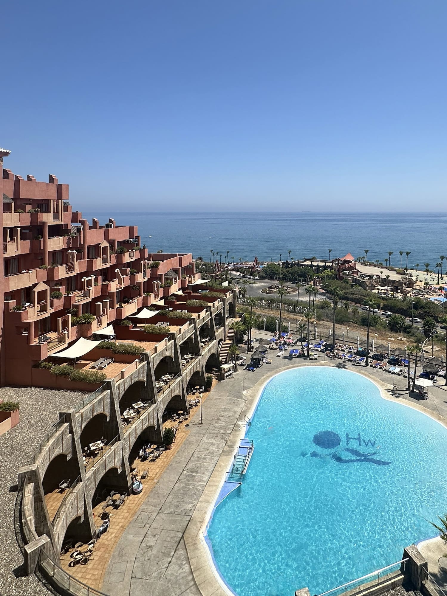 a pool with a large building and a beach